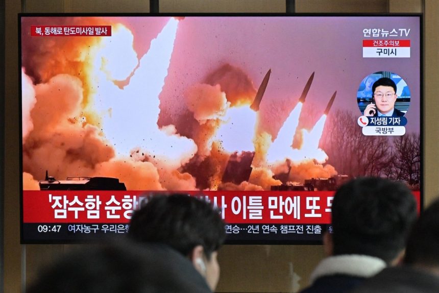People stand near a television showing a news broadcast with file footage of a North Korean missile test, at a railway station in Seoul on March 14, 2023. - North Korea fired two short-range ballistic missiles on March 14, 2023, Seoul said, Pyongyang
