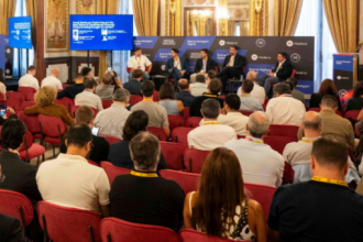 Un grupo de expectadores frente a un panel en un foro de criptomonedas en un auditorio de España.