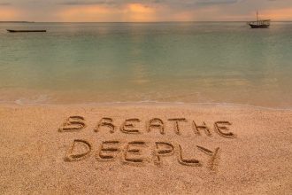 A beach at sunset where there is an inscription on the sand