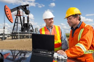 Two white male workmen working on site at an oil rig