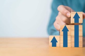 Businessman hand stacking up arrow on wooden block cubes