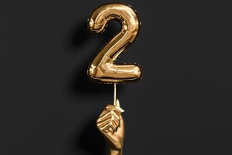 Golden hand holding Number 2 foil balloon.