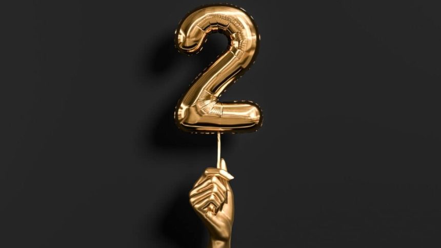 Golden hand holding Number 2 foil balloon.