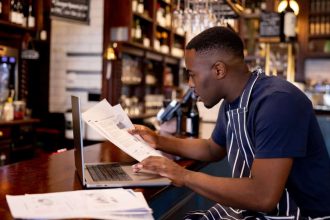 Business manager working at a pub doing the accountancy and some paperwork using a laptop computer