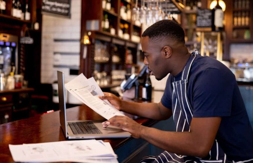 Business manager working at a pub doing the accountancy and some paperwork using a laptop computer
