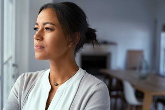 Young mixed-race woman looking out of the window with a look of consternation on her face