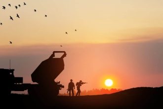 Artillery rocket system aimed to the sky and soldiers at sunset.