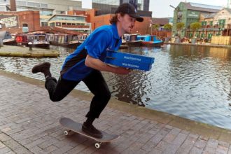Dominos delivery man on skateboard holding pizza boxes