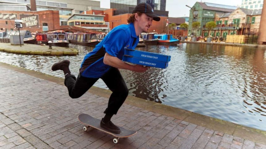 Dominos delivery man on skateboard holding pizza boxes