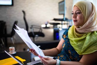Lady wearing a head scarf looks over pages on company financials
