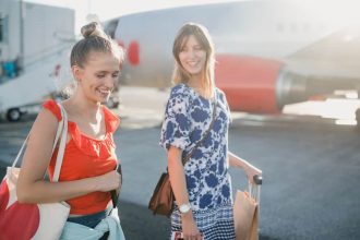 Young female couple boarding their plane at the airport to go on holiday.